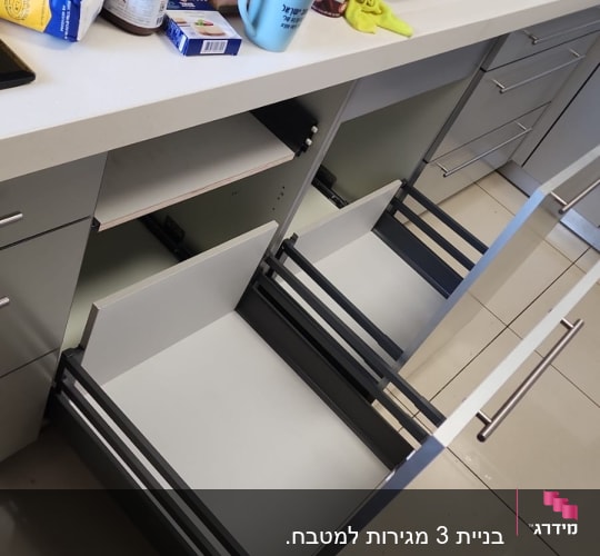 מגירות פתוחות במטבח עם מוצרים על השיש